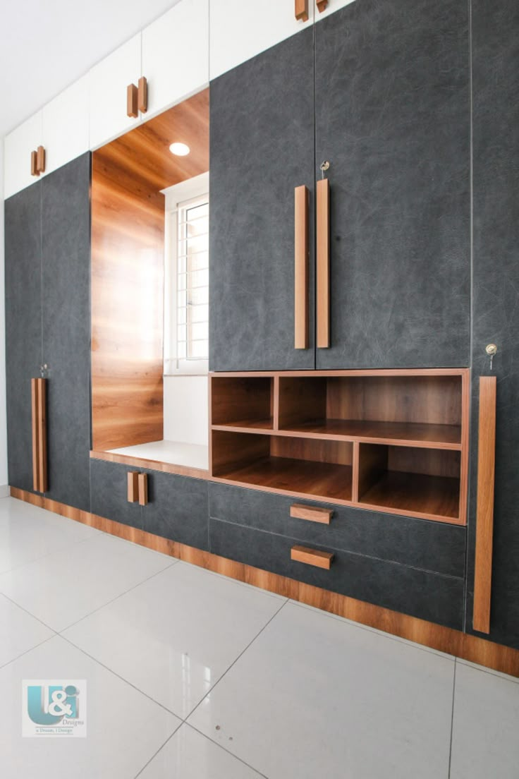 an empty room with wooden cabinets and white tile flooring on the wall, in front of a window