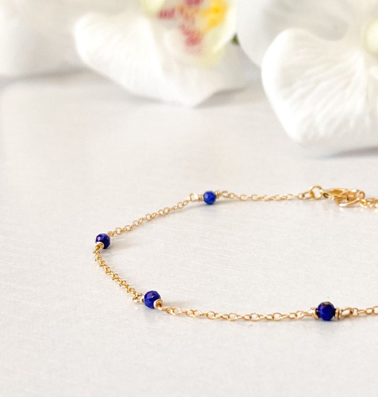 This beautifully simple bracelet is lovingly handmade with a six tiny Lapis Lazuli gemstones and a choice of 14k Gold Filled, 14k Rose Gold Filled or Sterling Silver Chain. M A T E R I A L S: * Lapis Lazuli * 14k Gold Filled, 14k Rose Gold Filled or Sterling Silver Chain S I Z E: *  Gemstones - Approximately 2-3mm *  Chain Thickness - Approximately 1.1mm  All of our jewellery is carefully handmade using good quality materials and handpicked gemstones, with the aim to produce quality pieces that you can love & wear for years to come.  L A P I S  L A Z U L I: * September Birthstone * Talisman for Taurus, Virgo, Libra, Sagittarius * Throat Chakra, Third Eye Chakra A stone of protection, Lapis Lazuli quickly releases stress, bringing deep peace. It brings harmony and deep inner self-knowledge. Tiny Beads Bracelet Jewelry Gift, Dainty Chain Bracelet With Tiny Beads As Gift, Elegant Blue Chain Bracelet As Gift, Elegant Blue Chain Bracelet For Gift, Dainty Chain Bracelet With Tiny Beads For Gift, Adjustable Blue Jewelry With Delicate Chain, Elegant Blue Bracelet With Delicate Chain, 14k Gold Filled Jewelry With Tiny Beads For Gifts, Delicate Bracelet Jewelry With Tiny Beads