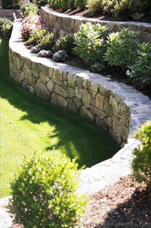 a stone wall and grass area in the yard