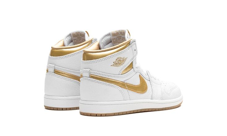 The Air Jordan 1 High OG PS "Metallic Gold" is the preschool sizing of Michael Jordan’s first signature shoe with flashy, head-turning gold details.  On this colorway, the timeless Jordan 1 High OG is designed with a white leather construction.  A Metallic Gold leather Swoosh is seen on each side of the shoe, and a Metallic Gold “Wings” logo appears on the collar.  More Metallic Gold is featured on the collar underlay and “Nike Air” branding on the tongue tag.  Underfoot, a white midsole and gol Gold High-top Basketball Shoes, Nike Yellow High-top Jordan Shoes, Jordan 1 Gold, Sporty Gold High-top Jordan Shoes, Jordan Gold, Metallic Gold Shoes, Jordan 1 High Og, Air Jordan 1 Retro High Og, Air Jordan 1 Retro High