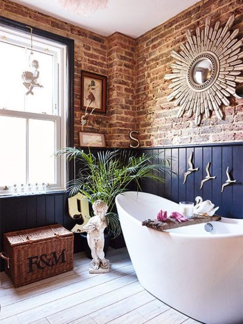 a bath tub sitting next to a window in a room with wooden floors and brick walls