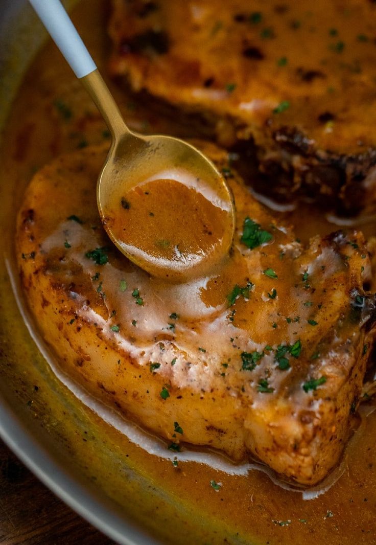 a wooden spoon is being used to stir some meat in gravy on a plate