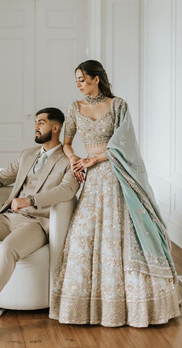 a man and woman sitting on a white couch in formal wear, posing for the camera