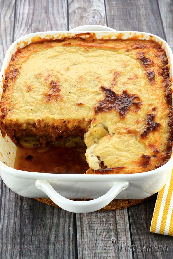 a casserole dish filled with meat and cheese on top of a wooden table