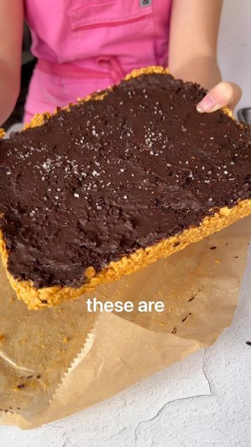 a piece of chocolate cake sitting on top of a brown paper bag next to a woman