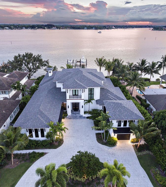 this is an aerial view of a home in the florida keys at sunset with water and palm trees