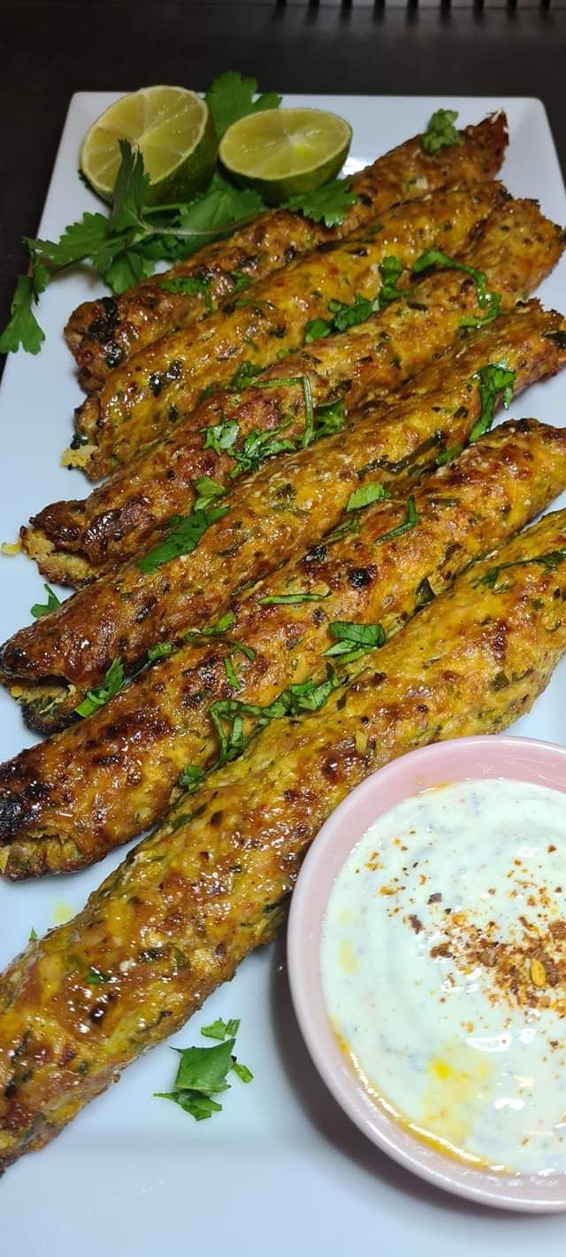 grilled fish sticks on a white platter with dipping sauce and garnishes