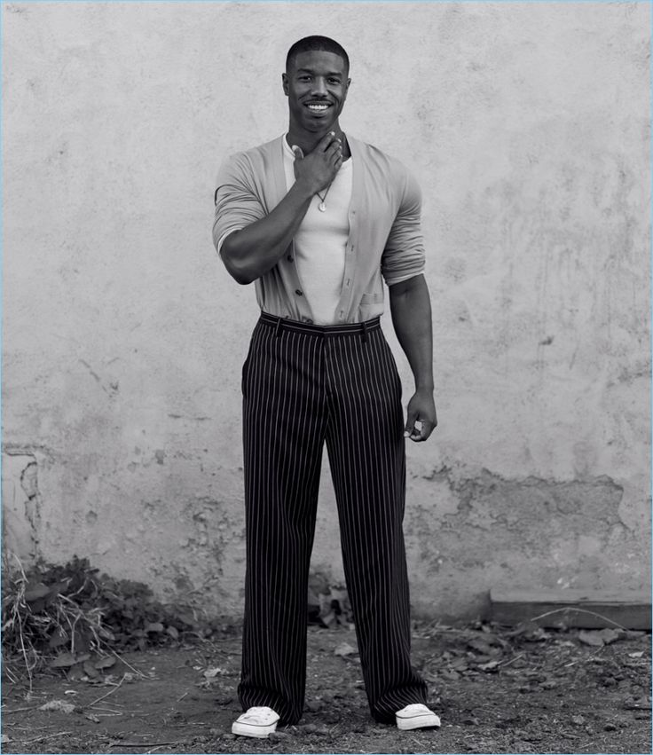 a man standing in front of a white wall with his hands on his chins