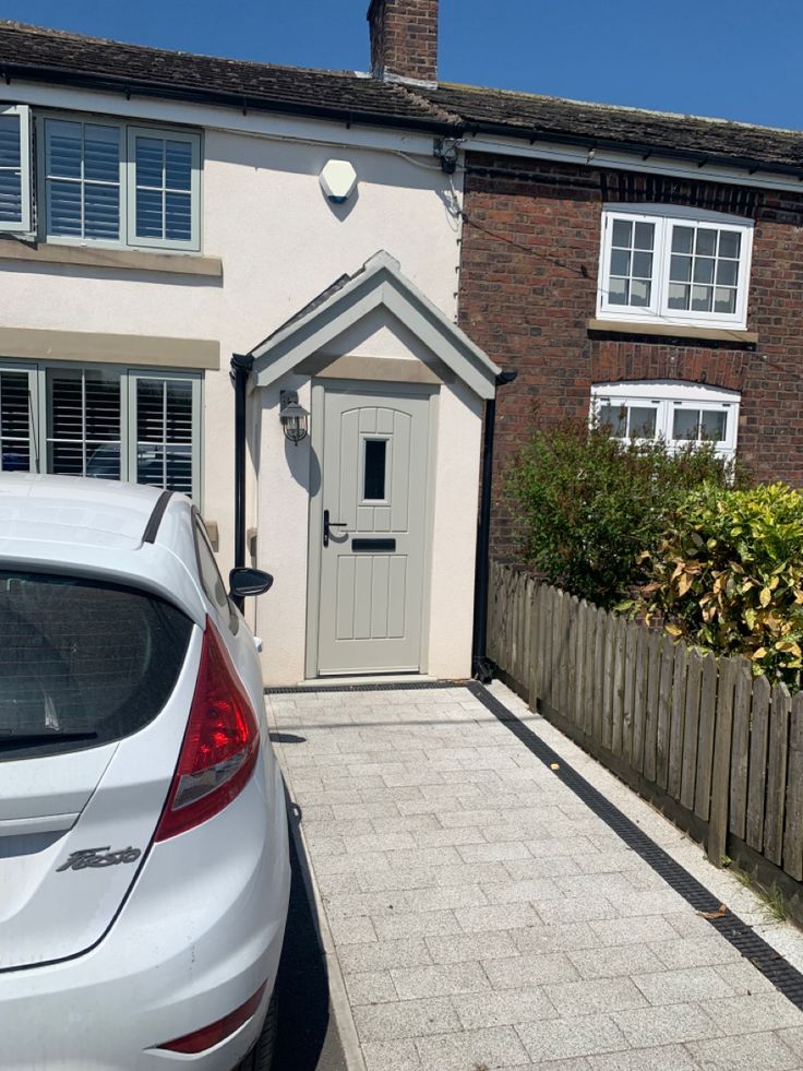 a white car is parked in front of a house with a wooden fence and gate