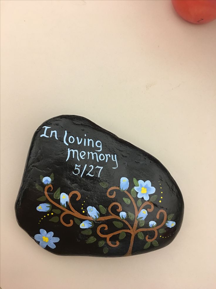 a rock with the words in loving memory written on it and flowers painted on it