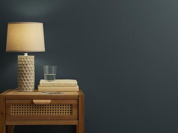 a table with a lamp and some books on it next to a glass vase filled with water