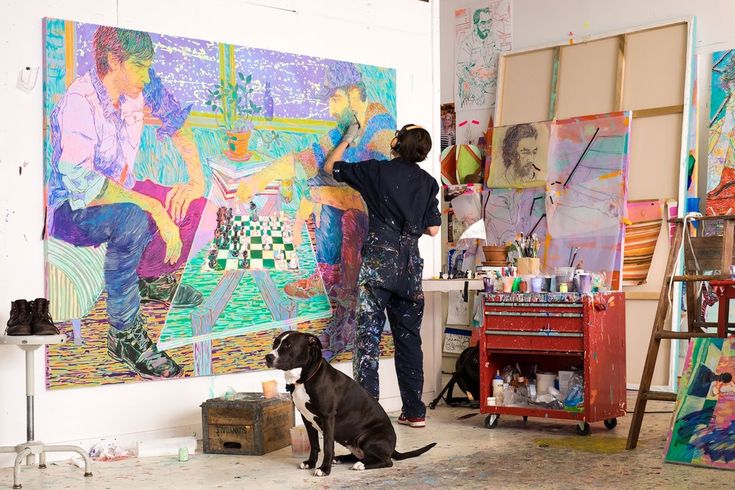 a man is painting on the wall with his dog in front of him and another person standing next to it