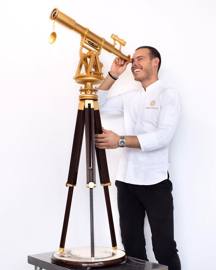 a man standing next to a telescope on top of a wooden stand and looking through it