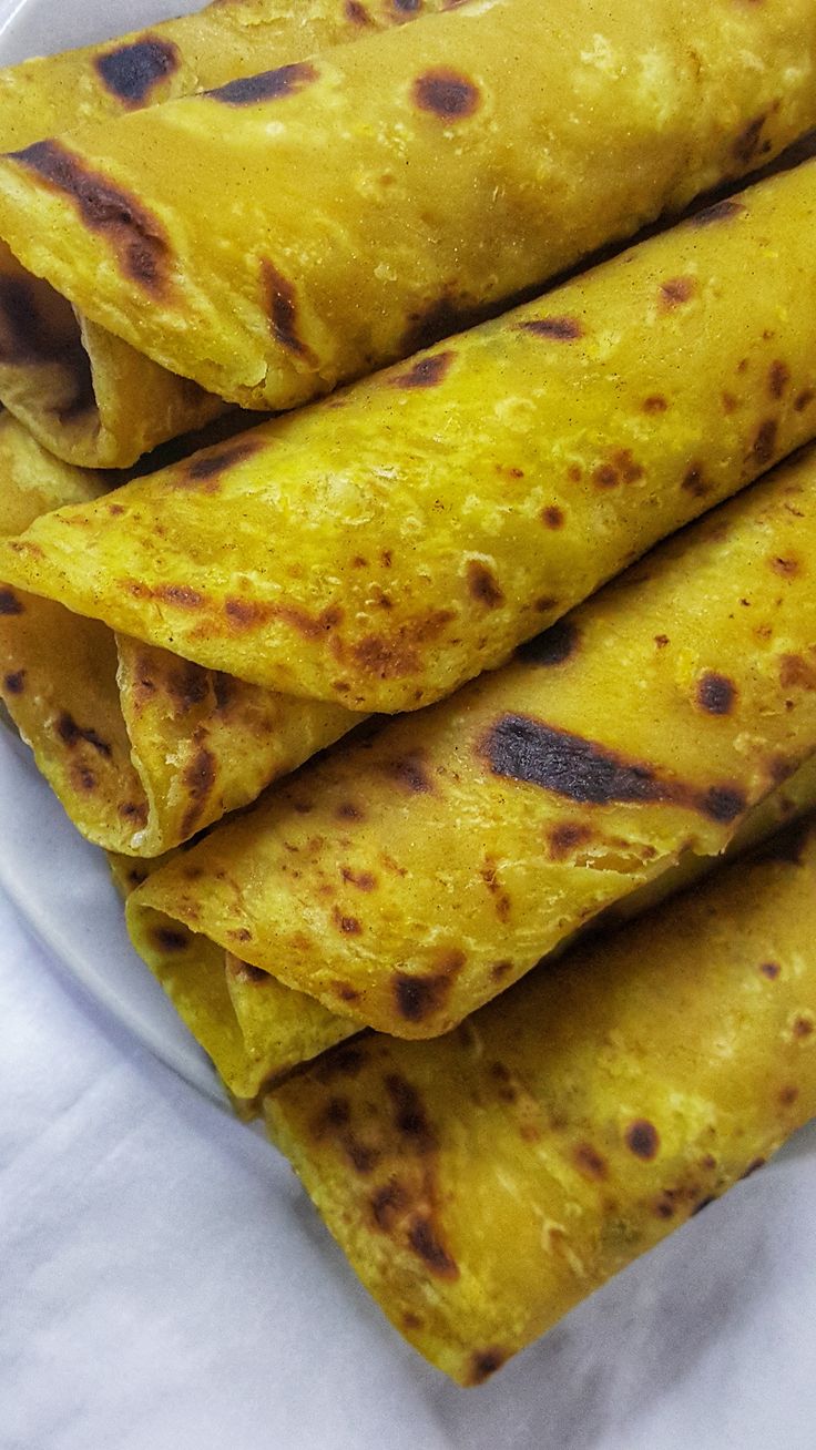 several tortillas stacked on top of each other in a white plate with napkins