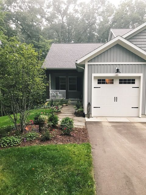 a house that has a driveway in front of it and trees around the garage door