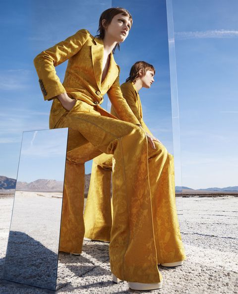 two women in yellow outfits sitting on top of a glass block with their legs crossed