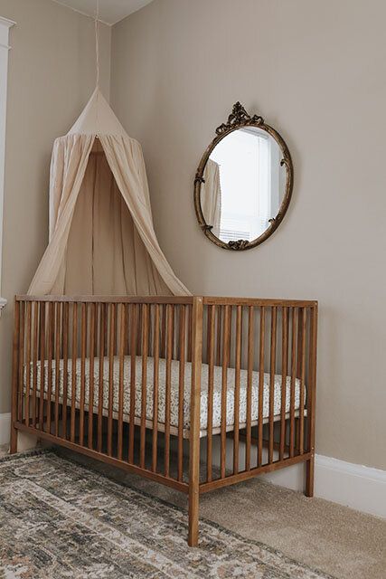 a baby crib with a mosquito net hanging from it's side and a mirror on the wall