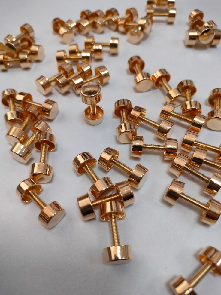 many gold colored screws are scattered on a white surface