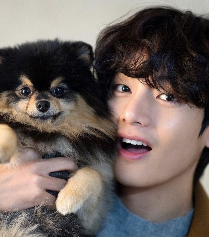 a young man holding a small dog in his arms and looking at the camera with an intense look on his face