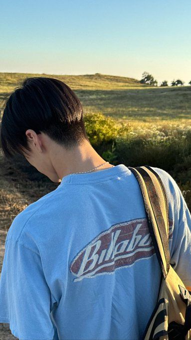 a man with a back pack looking out at the plains in the distance while standing on a dirt road