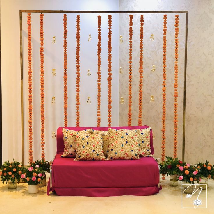 a red couch sitting in front of a wall with orange and pink flowers on it