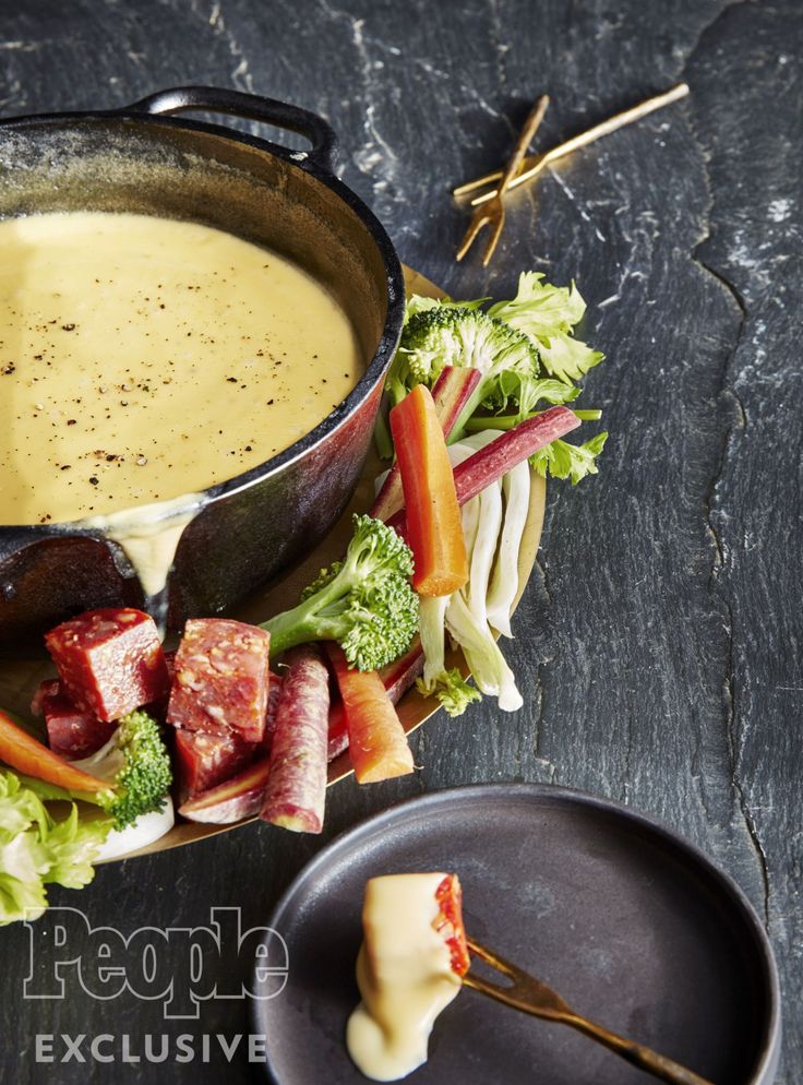 a bowl of soup with broccoli and carrots on the side next to it