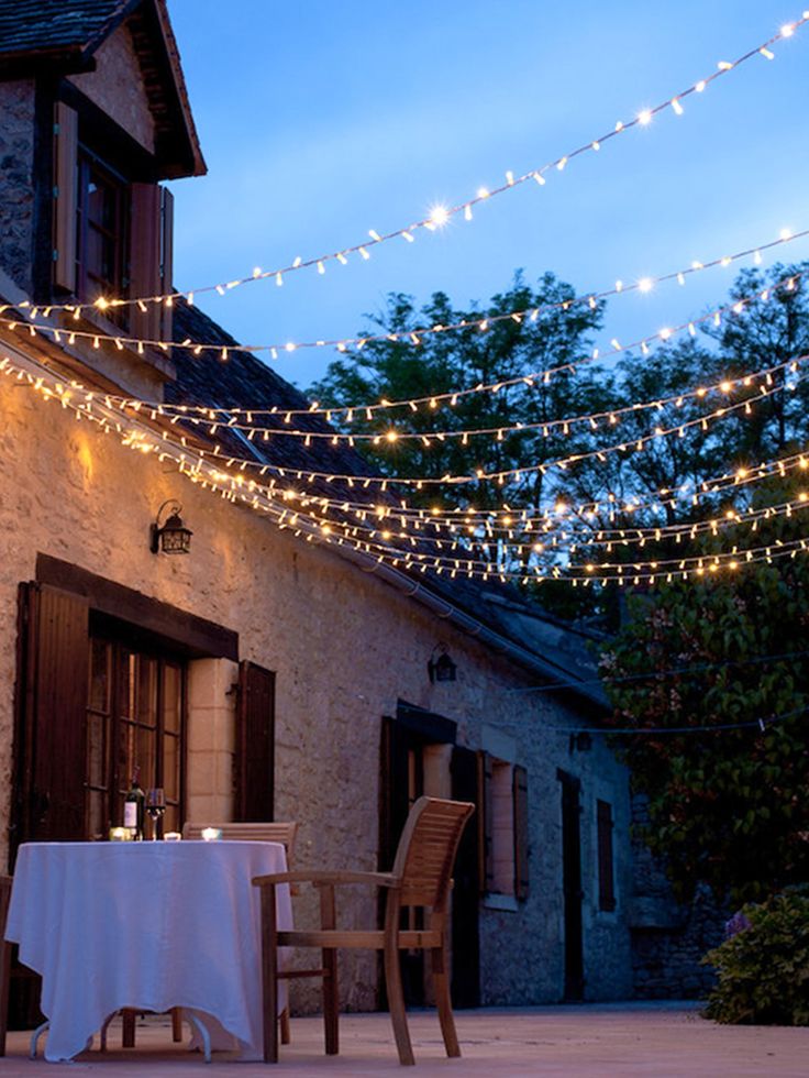 an outdoor dining area is lit up with fairy lights