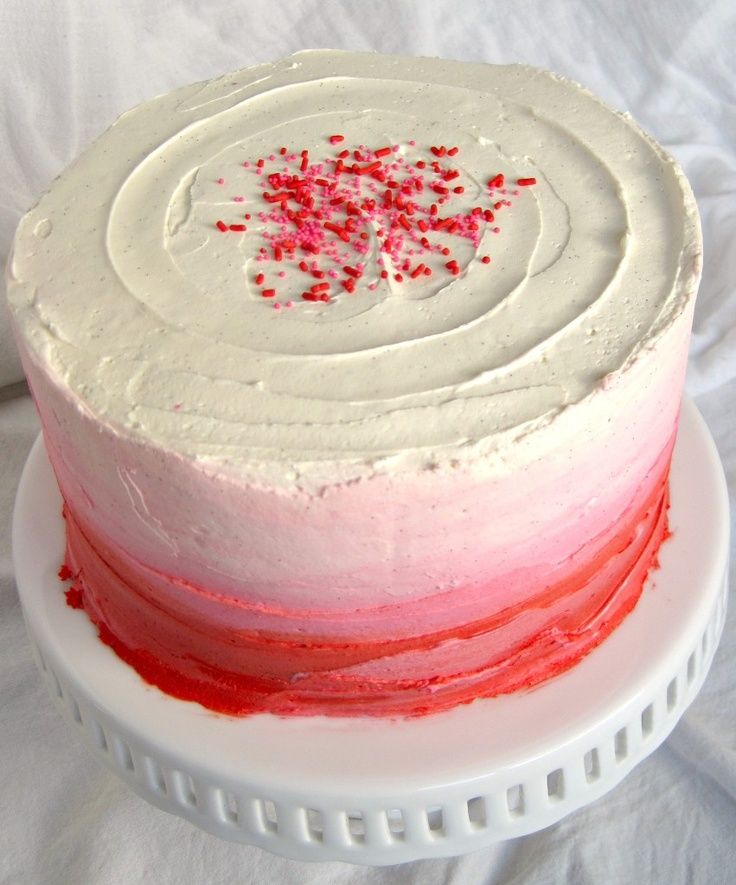 a cake with white frosting and red sprinkles sitting on a plate