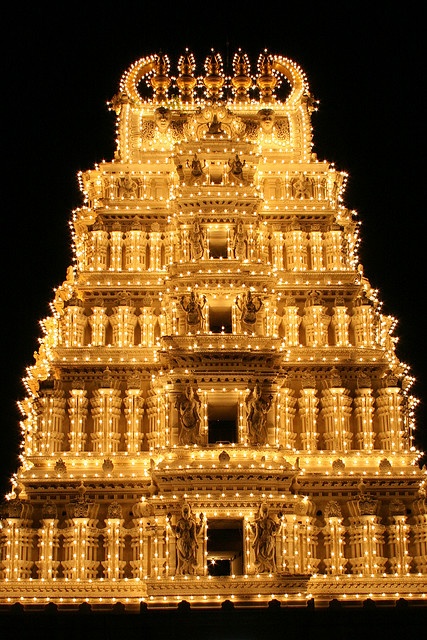 a very tall building with lights on it's sides and an intricately decorated top