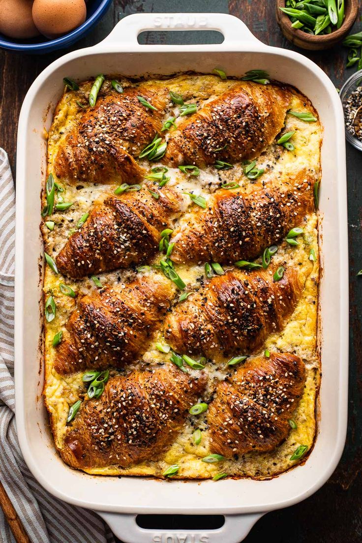 a casserole dish filled with chicken, cheese and green onions on a wooden table