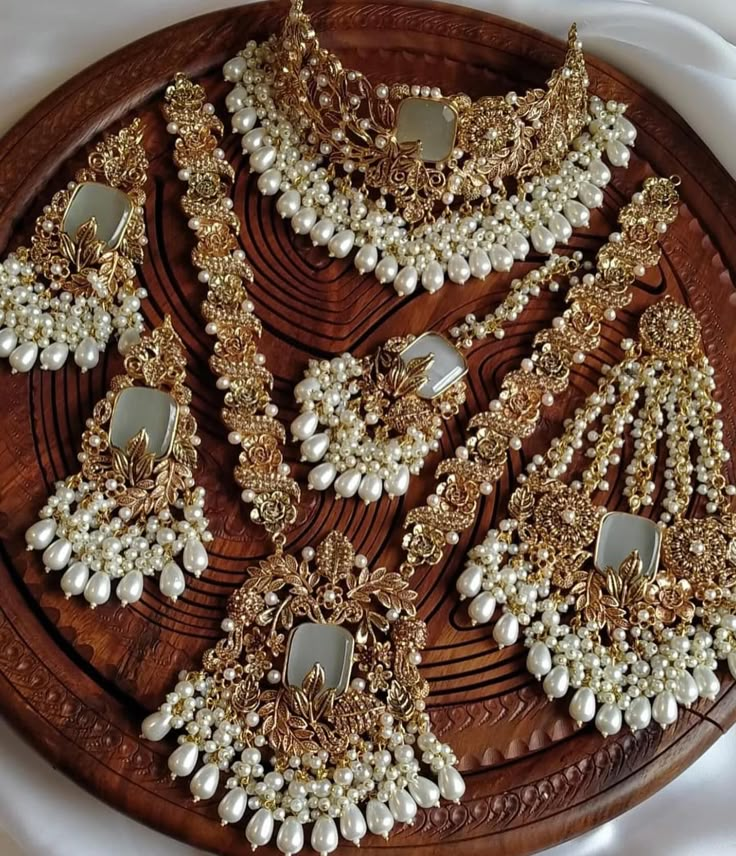 a wooden platter filled with white and gold jewelry