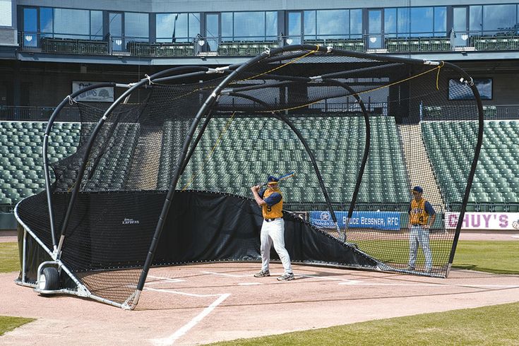 two baseball players are practicing in the batting cage