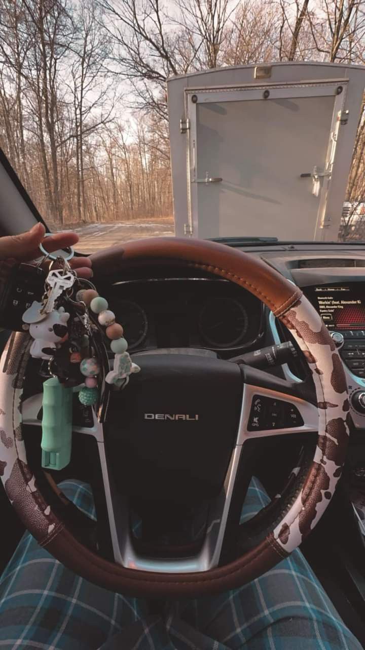 the steering wheel of a car with an open trunk in the background