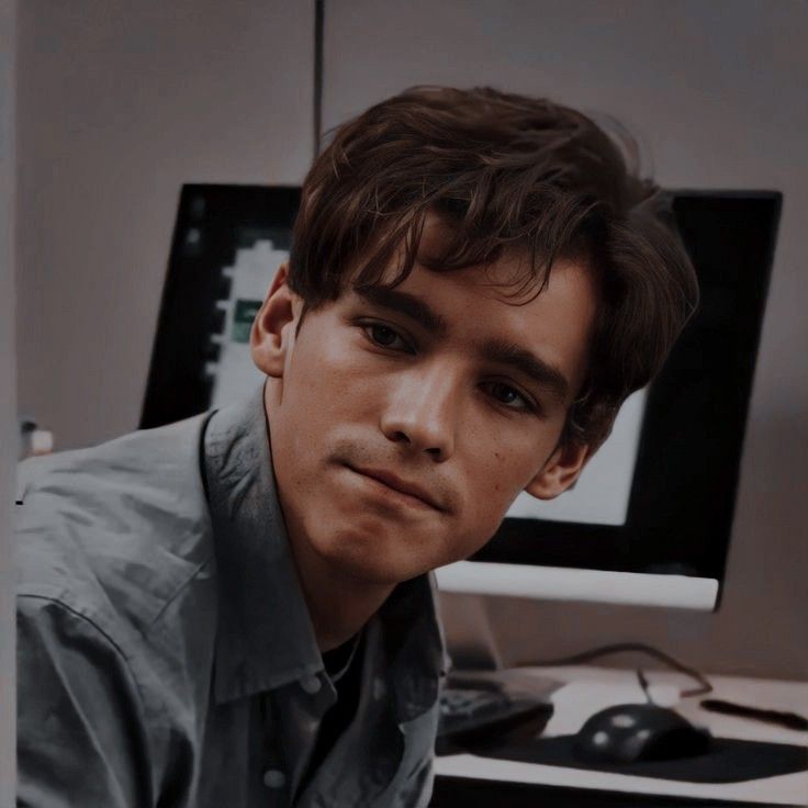 a young man is sitting in front of a computer desk with a keyboard and mouse