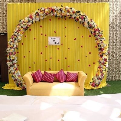 a couch sitting in front of a yellow backdrop with red and white pillows on it