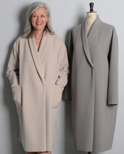 a woman standing next to a coat on a mannequin