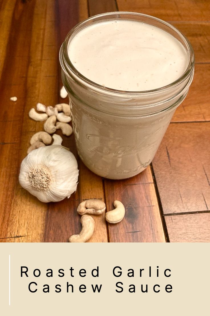 roasted garlic and cashew sauce in a glass jar on a wooden table with peanuts