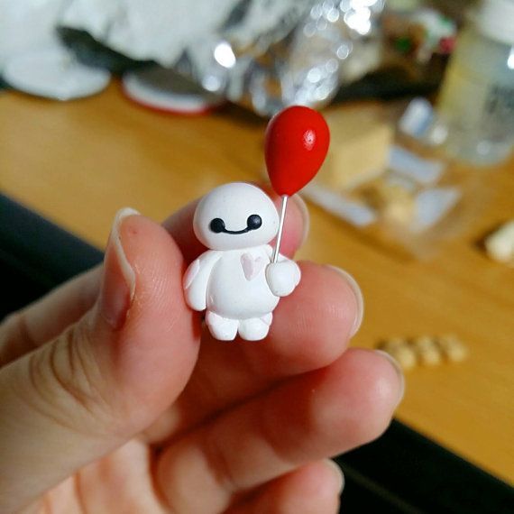 someone holding a tiny toy with a red balloon on it's tip in their hand