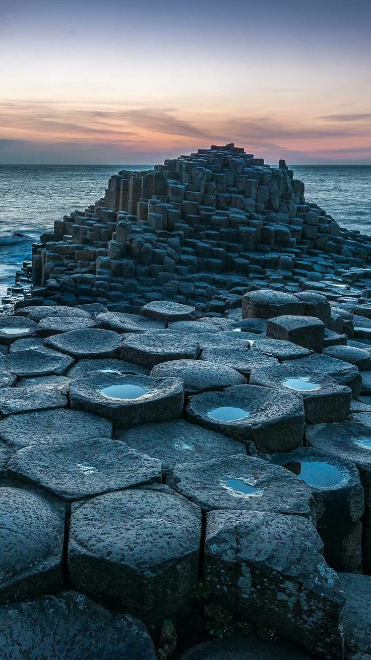 the giant stones are stacked up on top of each other by the ocean at sunset