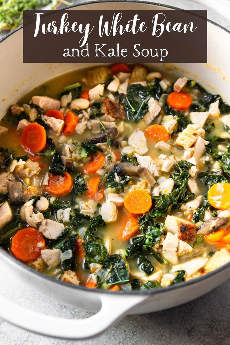 turkey white bean and kale soup in a pot with carrots, spinach