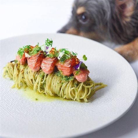 a white plate topped with pasta covered in sauce and garnished with toppings