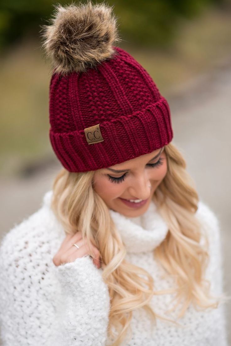 a woman wearing a red hat and white sweater with a pom - pom