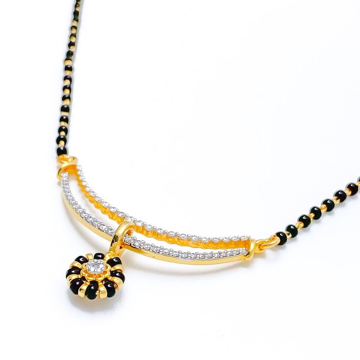 Elevate your style with our Floral Black Bead Drop Mangal Sutra. Crafted in 18k yellow gold, the diamond pendant boasts 0.56 ct diamonds in round brilliant cut, while the 22k black bead chain adds a bold contrast. Weighing 3.6 grams, this necklace is 19.5 inches long with an adjustable hook lock. PRODUCT DETAILS Diamond Pendant Gold Purity(karat): 18k Item Weight(grams): 3.6 Item Finish: Yellow Gold Stone: Diamond Diamond Weight(carats): 0.56 ct Diamond Color: F-G Diamond Quality: VS Diamond Sha Black 22k Gold Jewelry With Round Beads, Gold Necklaces With Black Diamonds, Traditional Yellow Gold Jewelry With Black Beads, Black 22k Gold Necklace For Weddings, Elegant Black Necklace For Celebration, Traditional Black Jewelry With Round Pendant, Black 22k Gold Jewelry As A Gift, Black 22k Gold Wedding Jewelry, Black 22k Gold Jewelry For Wedding