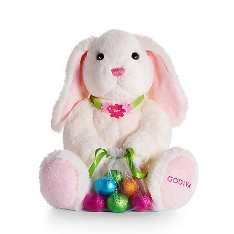 a white stuffed rabbit sitting next to an assortment of colorful easter eggs and candies