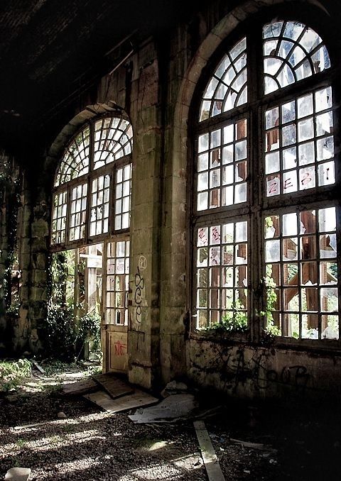 an abandoned building with three windows and graffiti on the walls