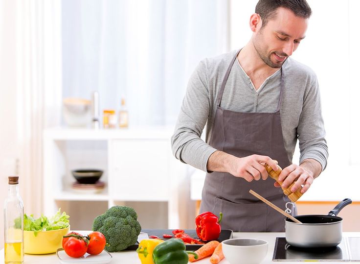 a man in an apron is cooking on the stove with vegetables and chopsticks