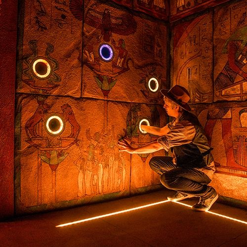 a man standing on top of a floor next to a wall covered in egyptian paintings