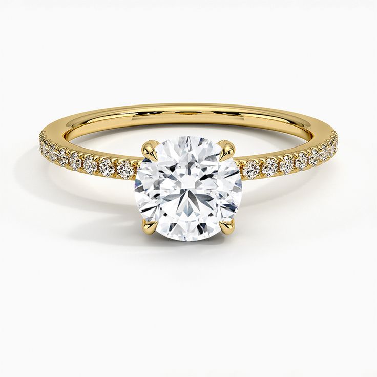 a yellow gold engagement ring with a round cut diamond in the center and pave set shoulders