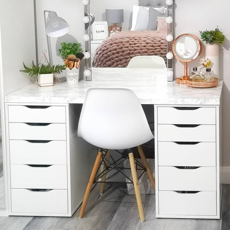 a white desk topped with a mirror and lots of drawers under a bed next to a chair