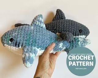 two crocheted shark stuffed animals being held by a hand